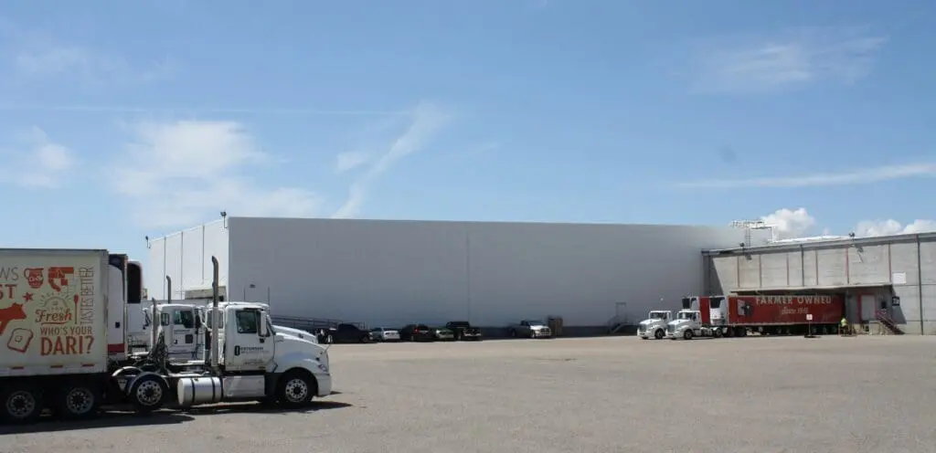 A truck is parked in front of a large warehouse.