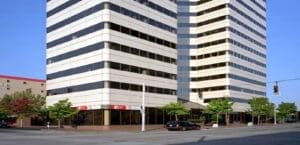 A tall building with a parking lot in front of it.