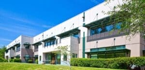 The exterior of an office building with grass and trees.
