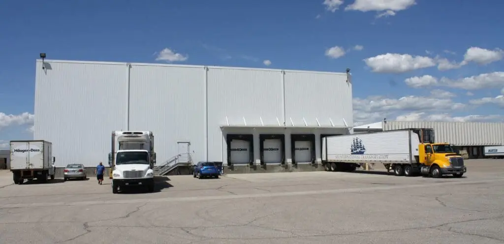 A large warehouse with trucks parked in front of it.