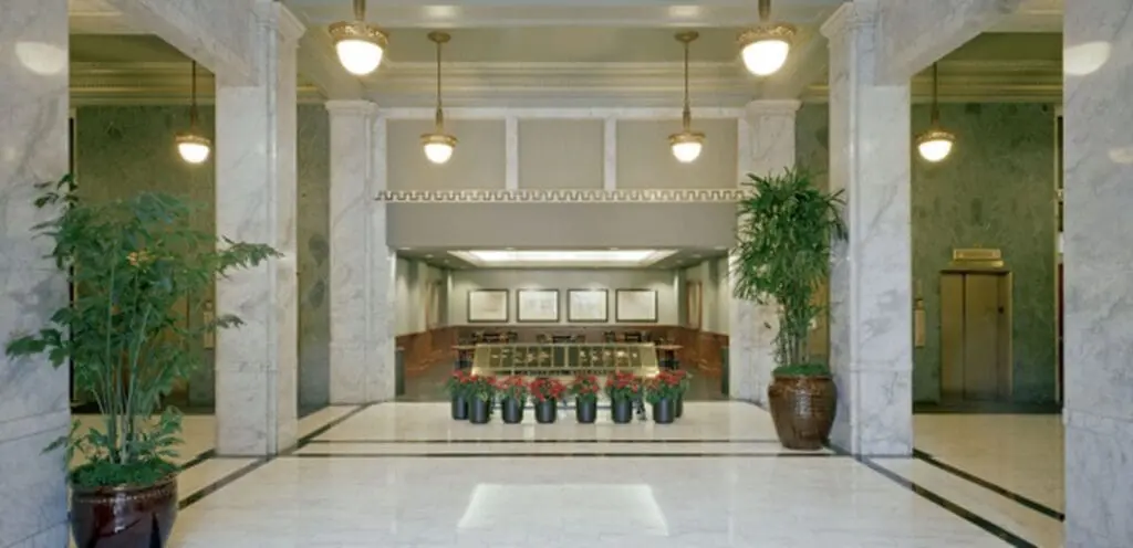 The lobby of a large building with marble floors and columns.